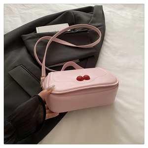 Detailed close-up of pink cherry handbag with wavy flap and adjustable shoulder strap