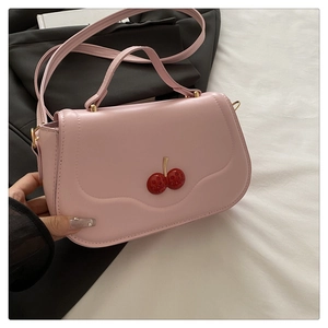 Detail of pink leather handbag featuring a red crystal-encrusted cherry metal clasp