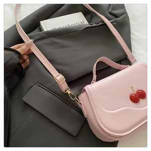 Detailed view of pink shoulder bag featuring a 3D cherry motif on a dark grey blazer