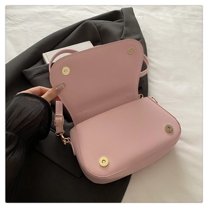 Detail of pink saddle bag featuring gold magnetic clasp and adjustable leather strap