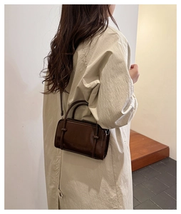 Detail of dark brown leather handbag showing fine texture and sleek strap on a model