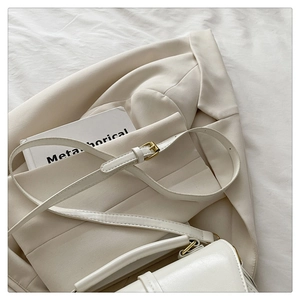 Chic cream leather crossbody bag styled with a blazer and book for an elegant look