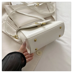 Bottom view of white leather crossbody bag showing light gold anti-wear metal feet studs