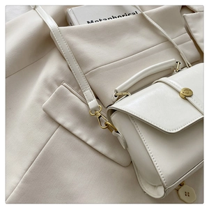 Detail of off-white PU leather handbag with bronze hardware and circular metal buckle