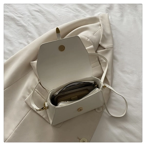 Detail view of the open white crossbody bag interior showing spacious storage and golden clasp
