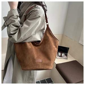 Detail of soft brown suede texture and leather strap on a spacious shoulder tote bag