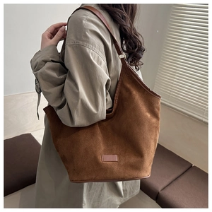 Detail of dark brown suede tote bag featuring leather shoulder strap and vintage aesthetic