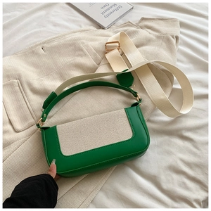 Detail of green leather and cream canvas patchwork crossbody bag with gold hardware