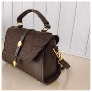 Détail du sac à main marron foncé montrant la texture suédée et le fermoir doré