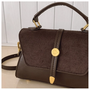 Détail d'un sac patchwork en cuir mat et lisse avec un accent métallique doré rond