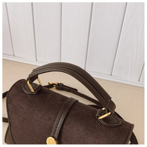 Vue détaillée du sac à main marron foncé en daim avec boucles métalliques dorées
