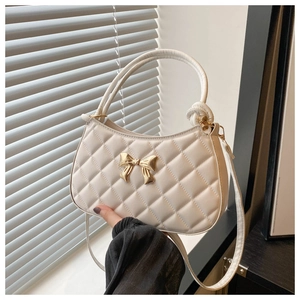 Détail du sac croissant matelassé blanc avec boucle papillon dorée et poignée ronde