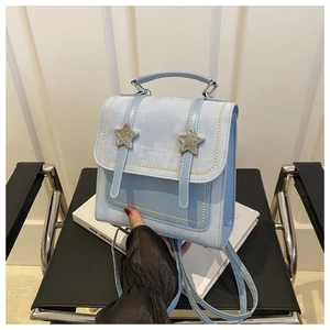 Detail of light blue backpack featuring suede flap and silver star-shaped metal buckles