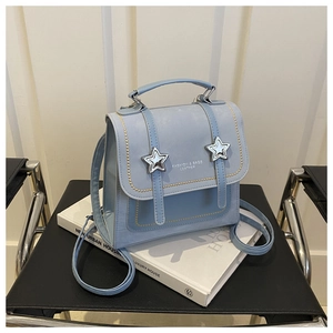 Detail of light blue faux leather backpack featuring silver star buckles and scalloped edges