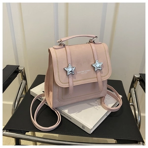 Detail of pink vintage mini backpack with star hardware and adjustable straps on books