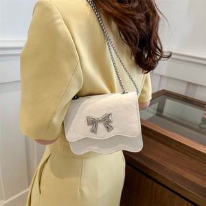 Elegante cremefarbene quadratische Tasche mit Schmetterlingsbogen und Kette