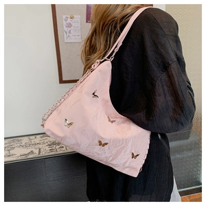 Detail of pink shoulder bag with gold butterfly charms and chain leather strap