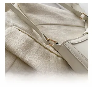 Close-up of golden metal buckle and fine stitching on the beige leather shoulder bag