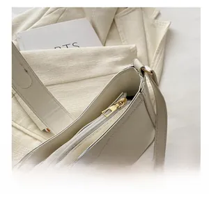 Detail shot of the smooth gold zipper and textured cream leather on the small square bag