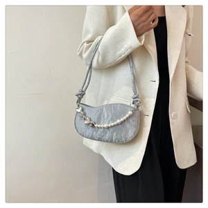 Detail of light blue pleated shoulder bag featuring elegant pearl chain and silver heart charms
