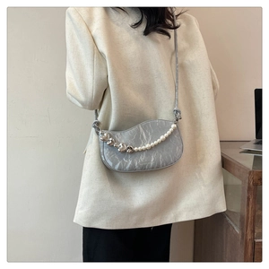 Detail of grey marble pattern crossbody bag with decorative pearl and heart chain strap