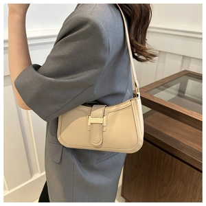 Close-up of beige crescent bag with smooth matte leather and gold-tone hardware