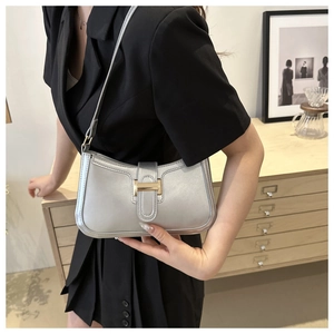 Detail of the golden H-shaped buckle on a silver metallic leather crescent shoulder bag