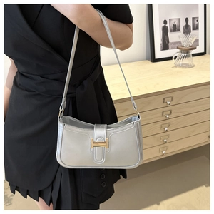 Detail of silver crescent shoulder bag with H-shaped metal clasp on model
