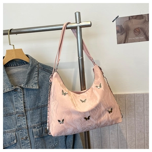 Pink pleated hobo bag with metal butterfly charms hanging on a metal hanger