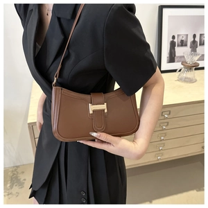 Detailed view of the vintage brown leather crescent bag with golden H-buckle hardware