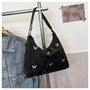 Detail of glossy pleated black hobo bag with silver butterfly charms and chain strap