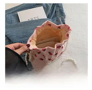 Detail of pink corduroy strawberry bucket bag with pearl strap and spacious interior
