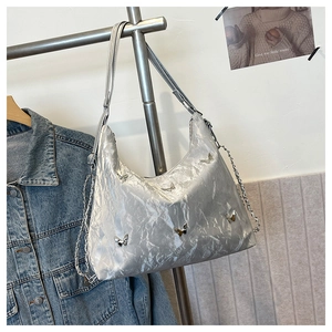 Close-up of silver pleated hobo bag with metallic butterfly accents and chain strap detail
