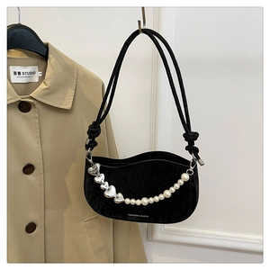 Detail of black underarm bag featuring wave texture, silver heart, and pearl chain ornament
