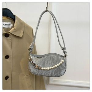 Detail of silver crescent shoulder bag with metallic heart chain and pearl accents