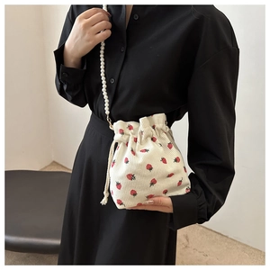 Detail of corduroy bucket bag with strawberry print and elegant pearl chain strap