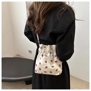 Detail of strawberry embroidery on corduroy bucket bag with elegant pearl strap