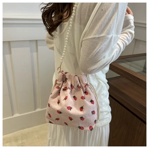 Detail of pink corduroy bucket bag with strawberry print and pearl chain strap