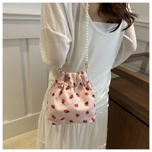 Detailed view of pink corduroy strawberry bucket bag with white pearl beaded strap