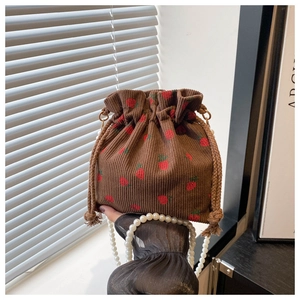 Detail of strawberry corduroy bucket bag featuring luxury pearl beaded handle and drawstring