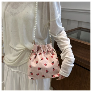 Pink corduroy bucket bag with strawberry print and white faux pearl shoulder strap