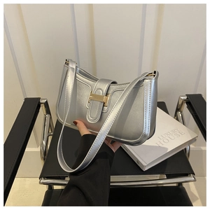 Detail of silver metallic handbag with a golden clasp shown in an indoor setting