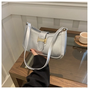 Close-up of silver crescent handbag with H-shaped metal buckle in a cafe setting