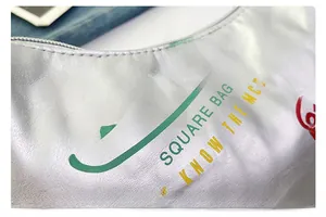 Dettaglio della borsa a mezzaluna argento con scritte graffiti e chiusura a zip