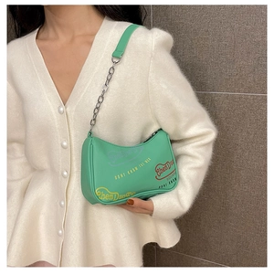 Dettaglio della borsa sottobraccio verde menta con catena in metallo e stampe moda