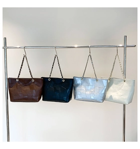 Detail view of four large tote bags in brown, black, silver, and cream with chain straps