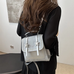 Silver-gray faux leather backpack with metallic star accents and adjustable straps