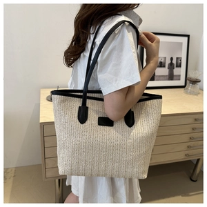 Détail d'un sac cabas tissé beige avec des lanières en cuir noir pour l'été