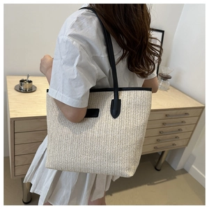 Détail du sac cabas beige tressé avec poignées et finitions en cuir noir