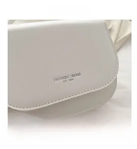 Close-up of white leather saddle bag showing silver Fashion Trend 1996 text and fine stitching